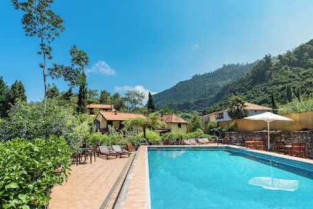 Una piscina al aire libre, sombrillas, sillones reclinables de piscina