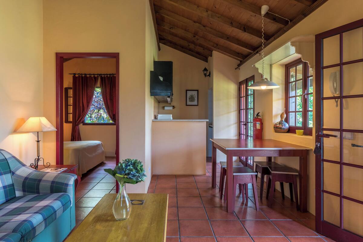 A cozy room with a sofa, a dining table, and a kitchen area.