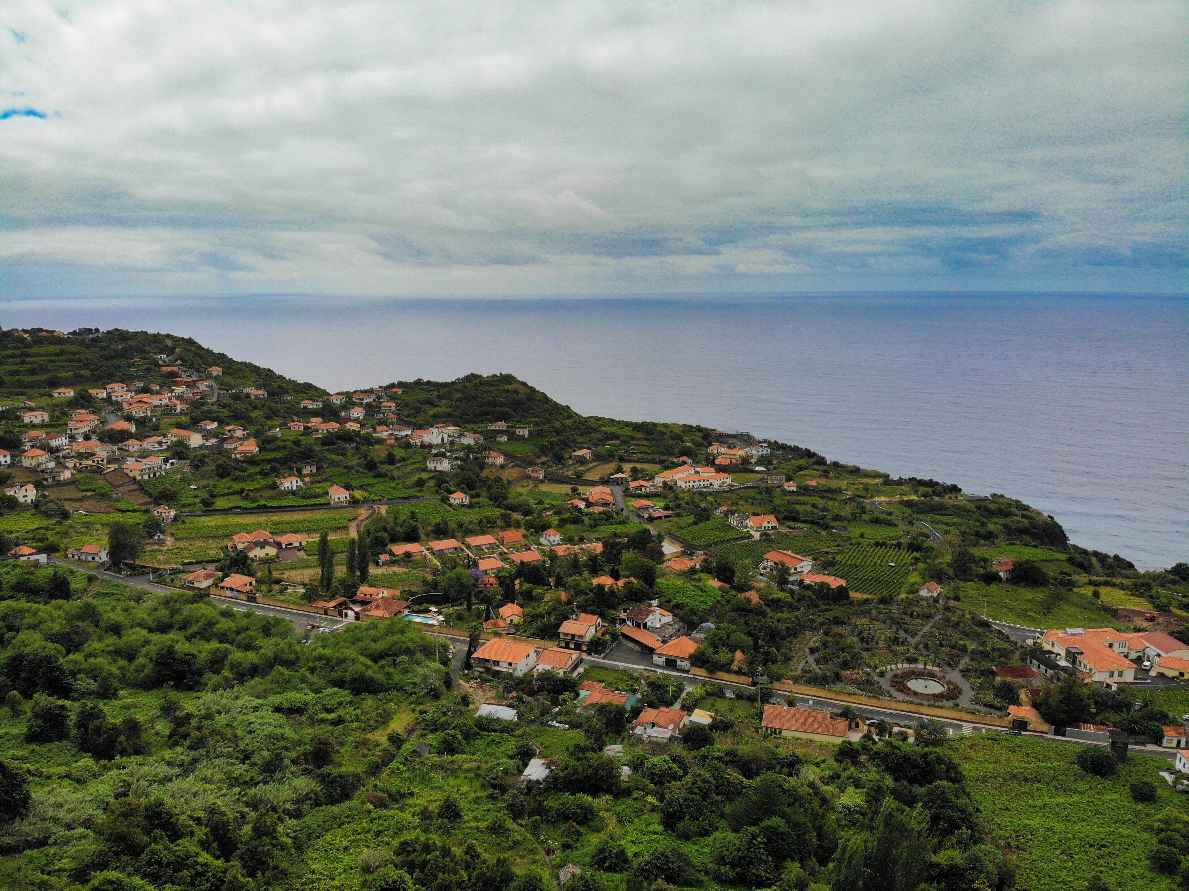 A coastal village with houses on a hillside, a road, and a view of the sea.