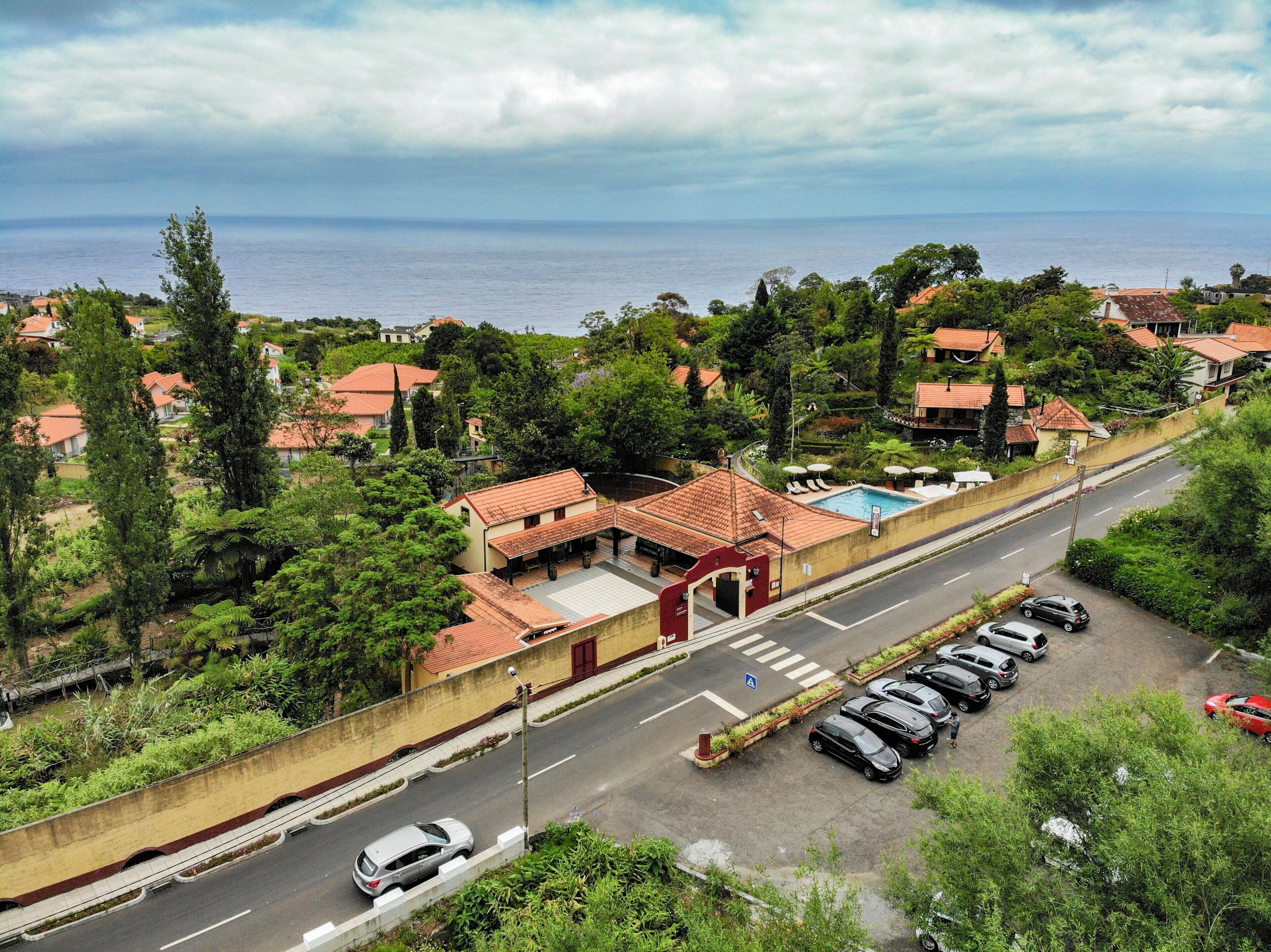Un quartiere residenziale con piscina, auto parcheggiate e vista sul mare.