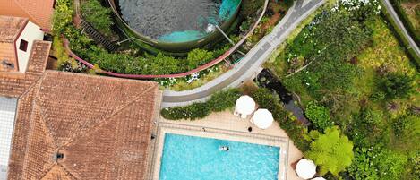 Oversigtsbillede af et resort med swimmingpool, loungeområde og frodig beplantning omkring.