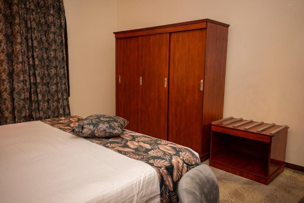 Un dormitorio con cama, armario y un pequeño banco de madera.