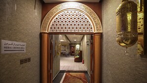 A hallway leading to the MERAL CROWN HALL with a patterned archway and a sign indicating the location. - Meral Crown Hotel (Riyadh)