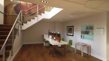 Ein modernes Interieur mit einer Treppe, einem Empfangstresen und einer Wand mit Informationspostern.