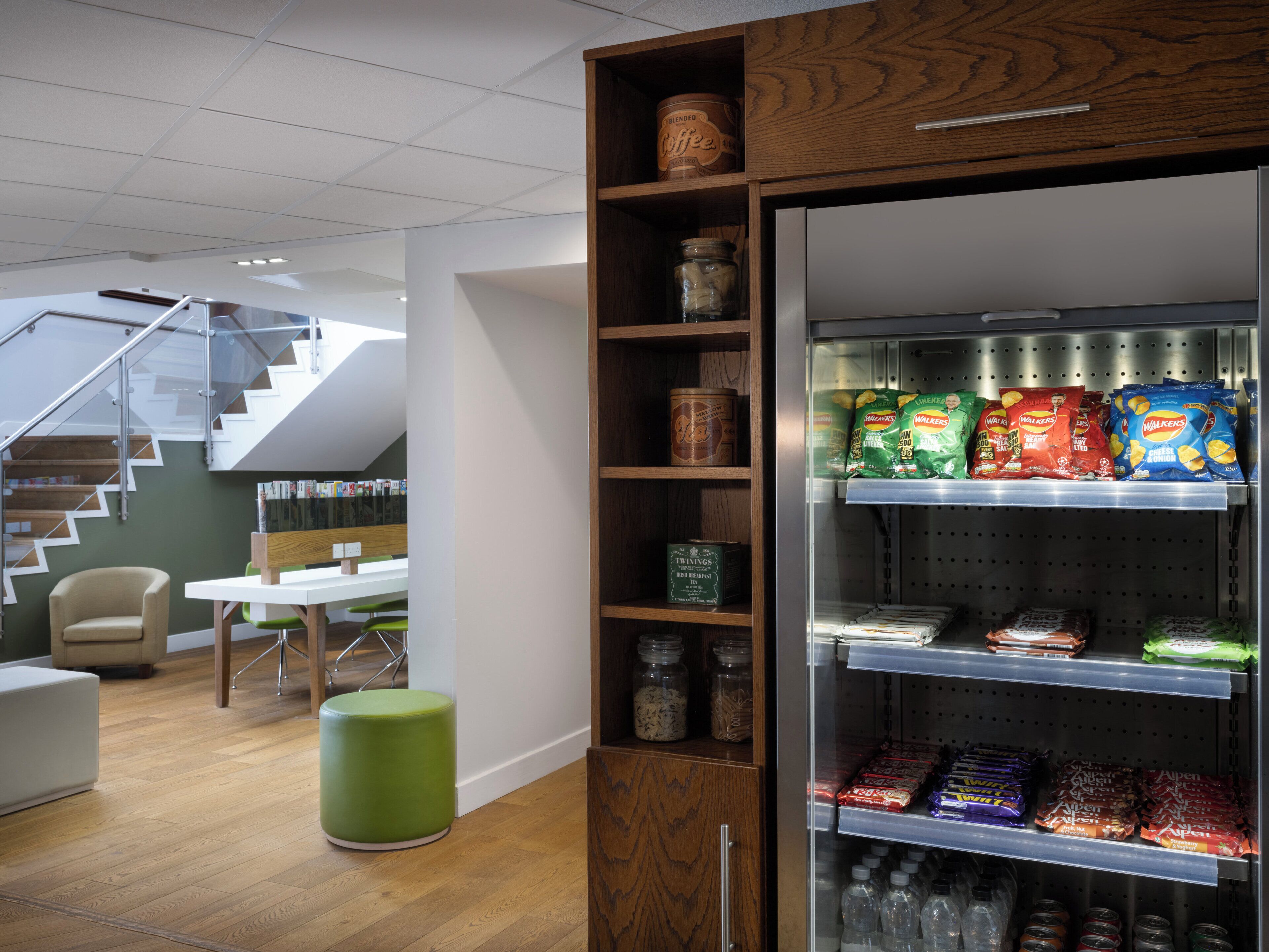 A modern interior with a staircase, a seating area, and a snack vending machine.