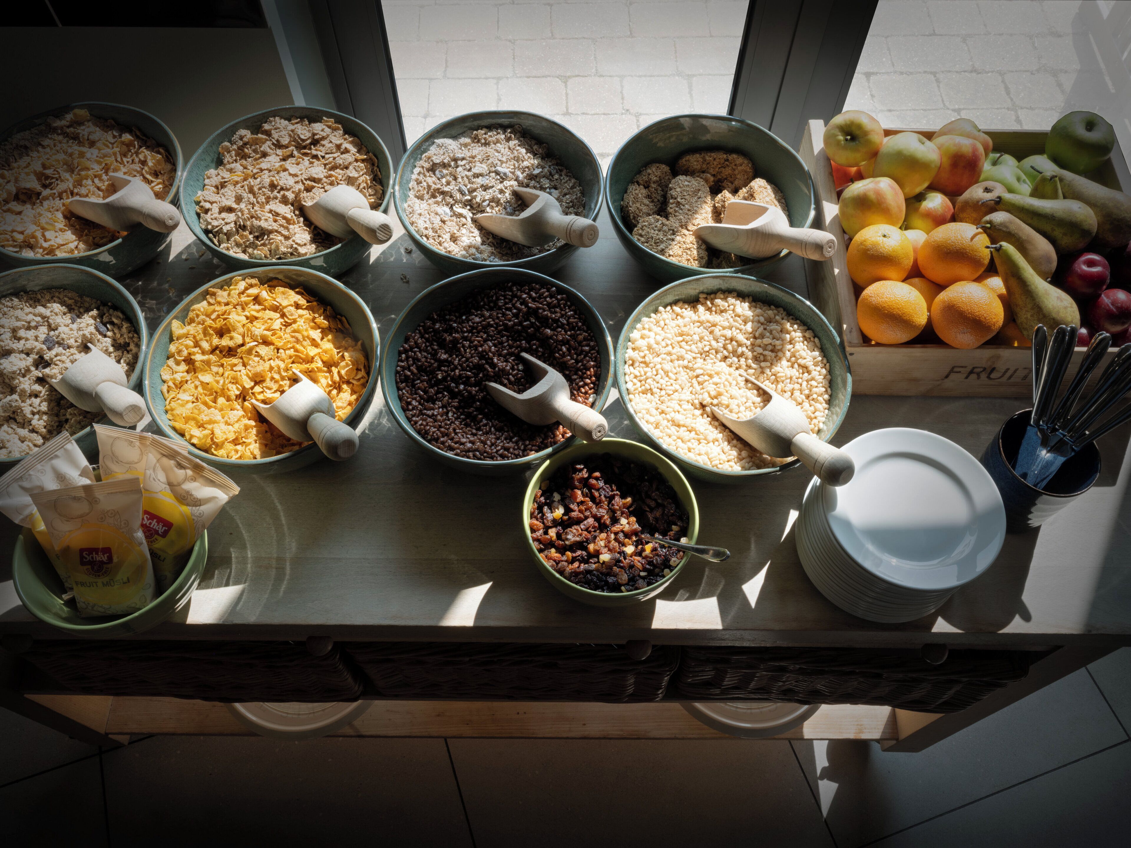 A breakfast buffet with various cereals and fruits.