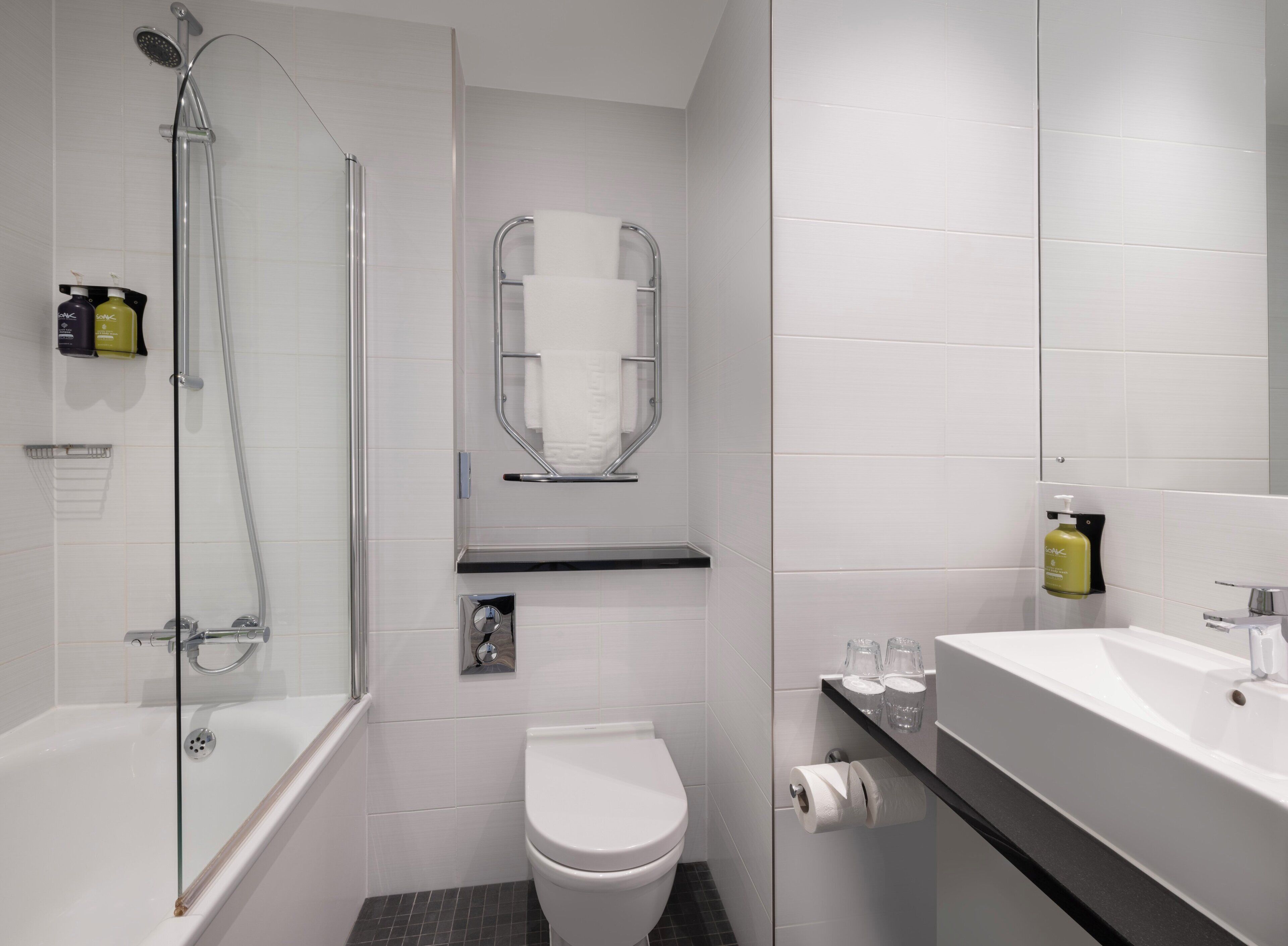 A modern bathroom with a glass-enclosed shower, a toilet, and a sink with a mirror.
