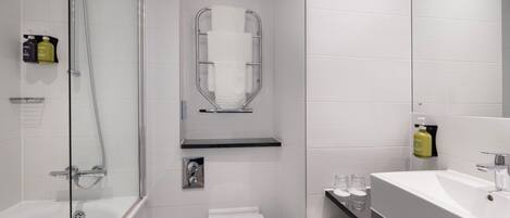 A modern bathroom with a glass-enclosed shower, a toilet, and a sink with a mirror.