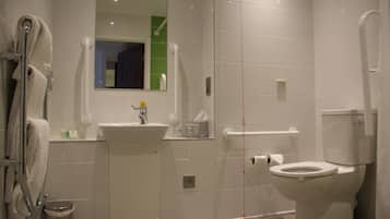 Un baño moderno con inodoro, lavamanos y barras de apoyo.