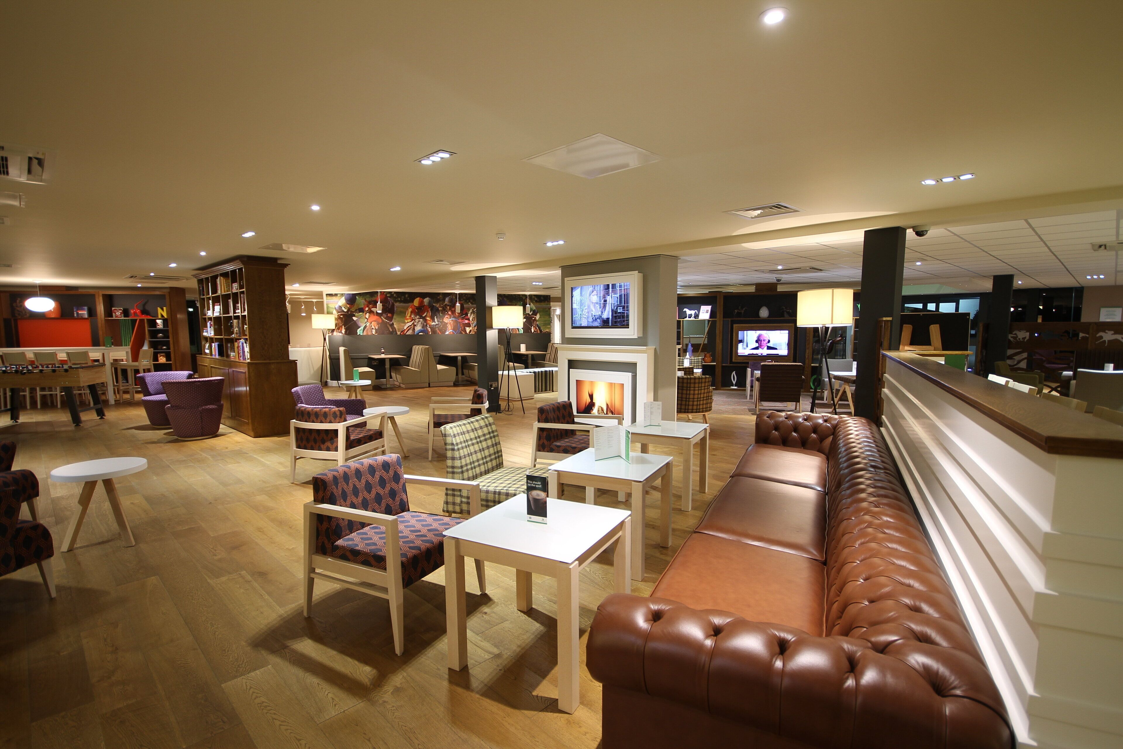 A hotel lobby with seating areas, a fireplace, and a television screen.