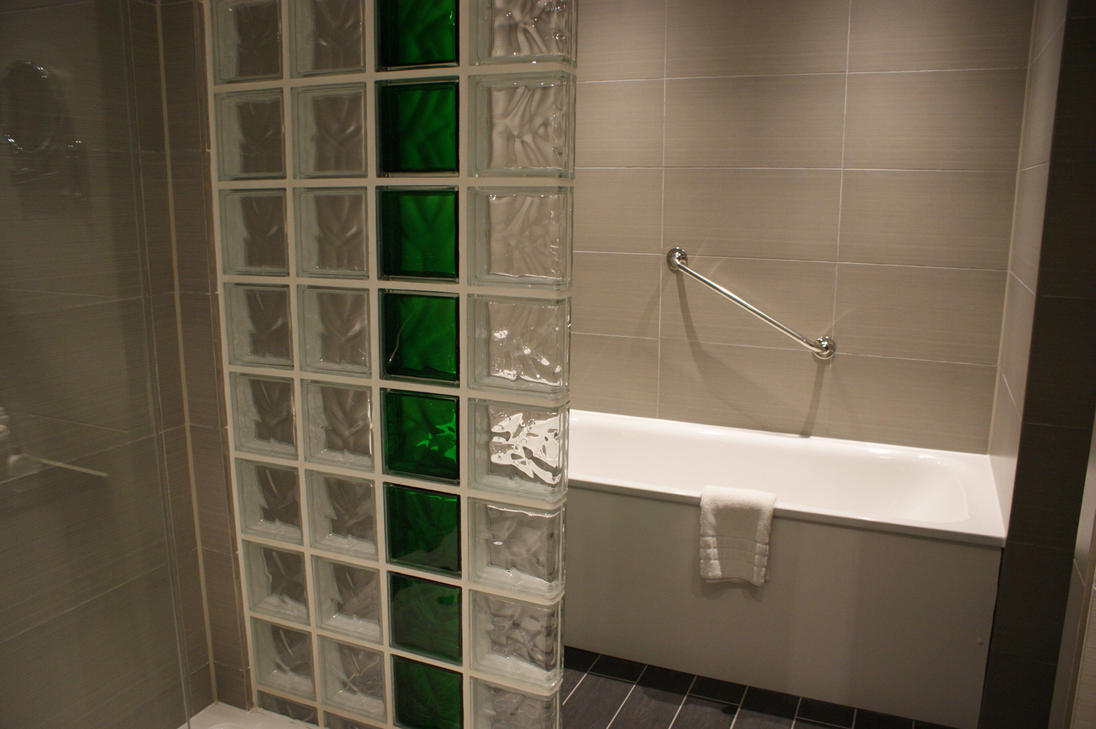 Un baño con cabina de ducha de vidrio, una bañera blanca y un perchero para toallas.