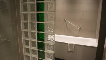 Un baño con cabina de ducha de vidrio, una bañera blanca y un perchero para toallas.