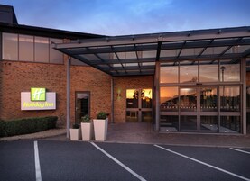 Un Holiday Inn con fachada de ladrillo, un amplio acceso de vidrio y un área exterior cubierta.