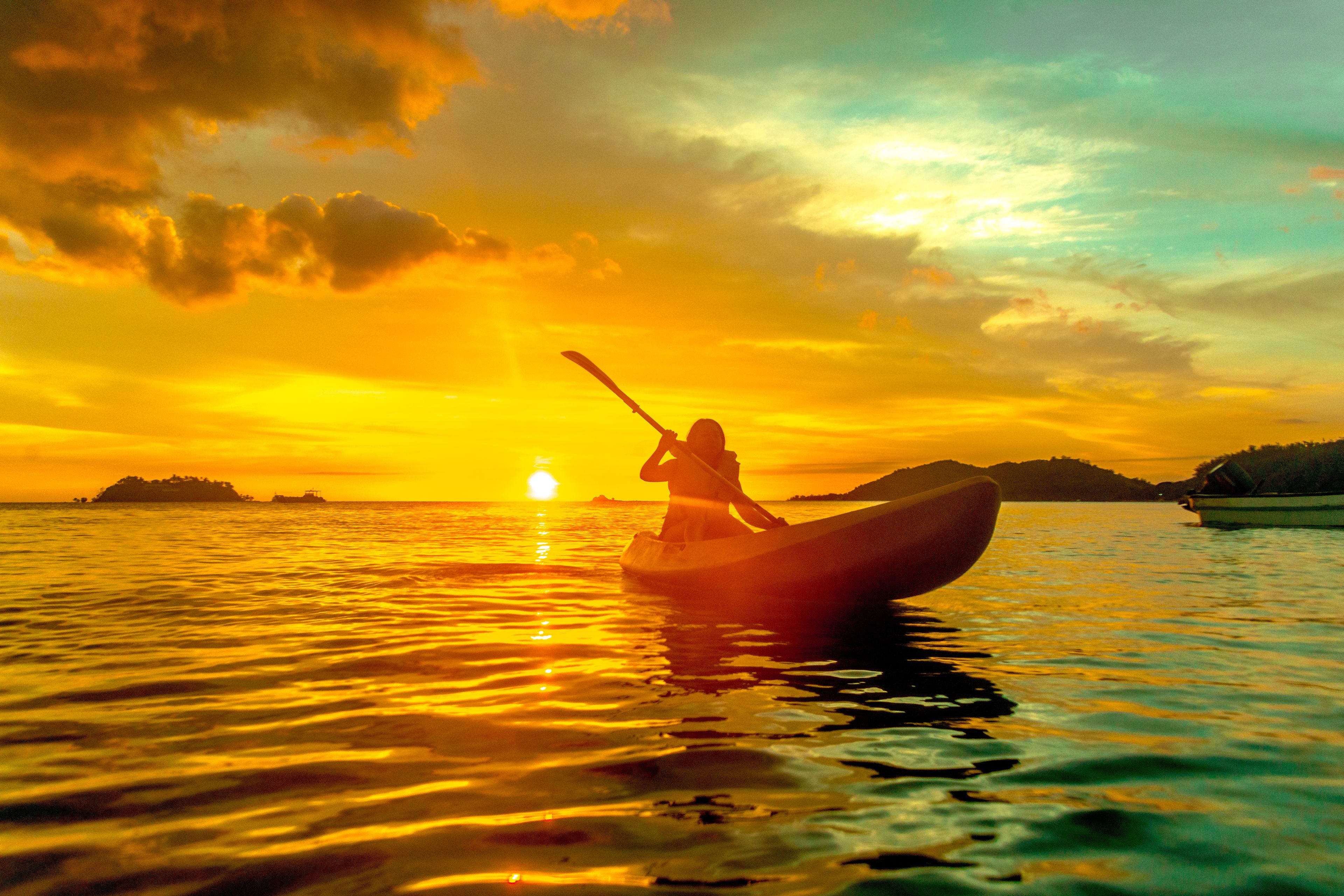 A sunset over water with a person in a kayak.