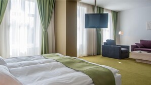 Una habitación de hotel con una cama grande, televisión, escritorio y silla.