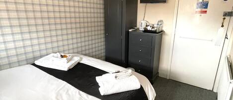 A hotel room with two beds, a wardrobe, a television, and a door with a fire action sign.