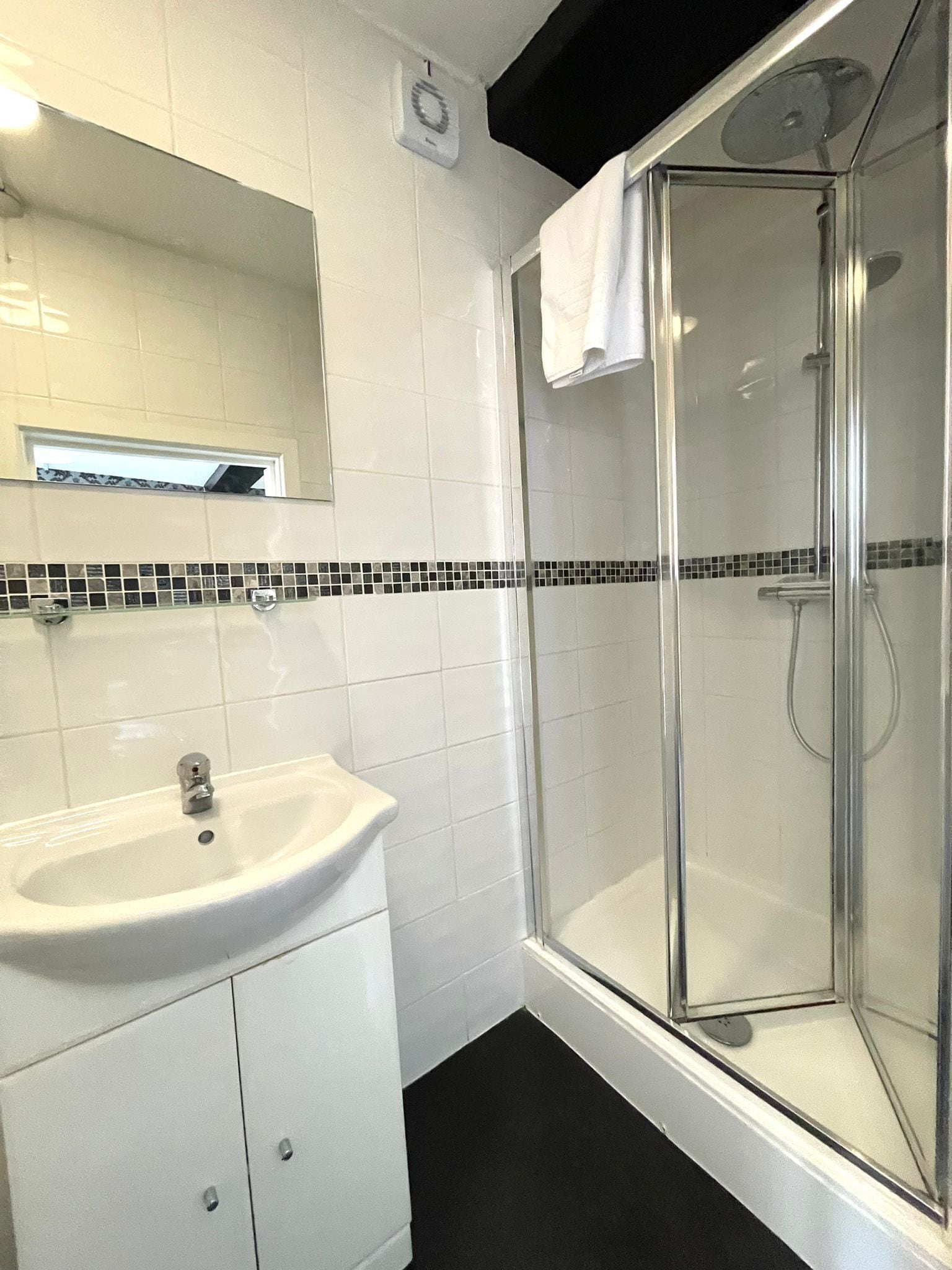 A bathroom with a white sink, a mirror, and a glass-enclosed shower.