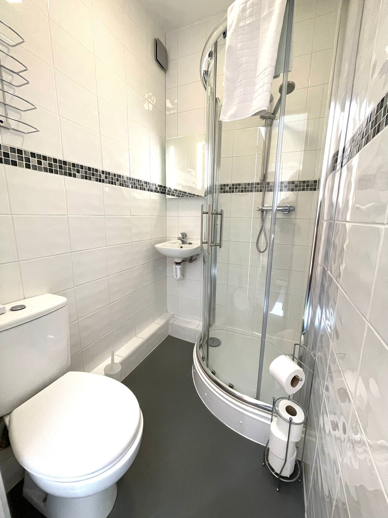 A modern bathroom with a toilet, sink, and glass-enclosed shower.