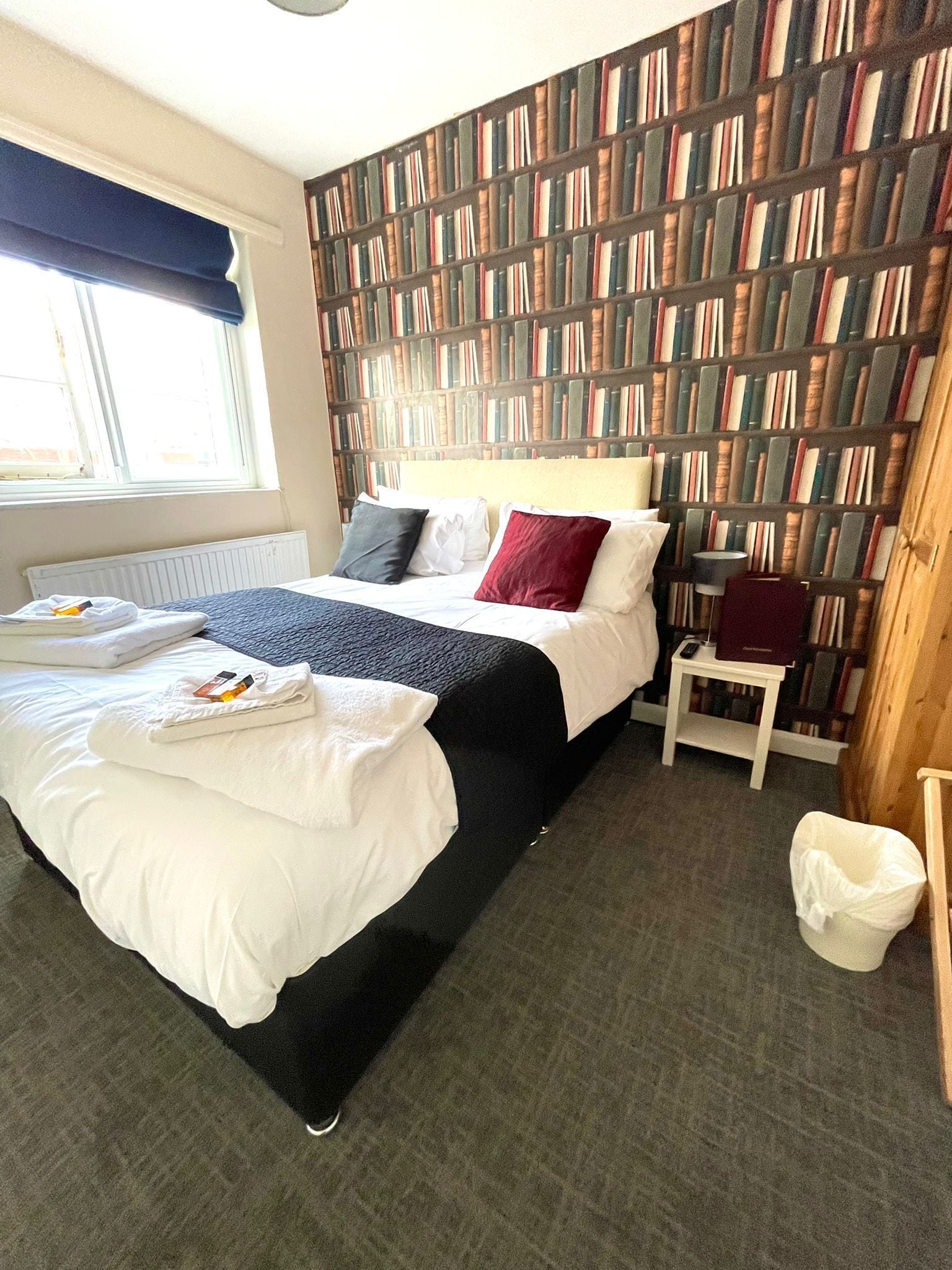 Et hotelværelse med en stor seng, en reol, et lille bord og en radiator.
