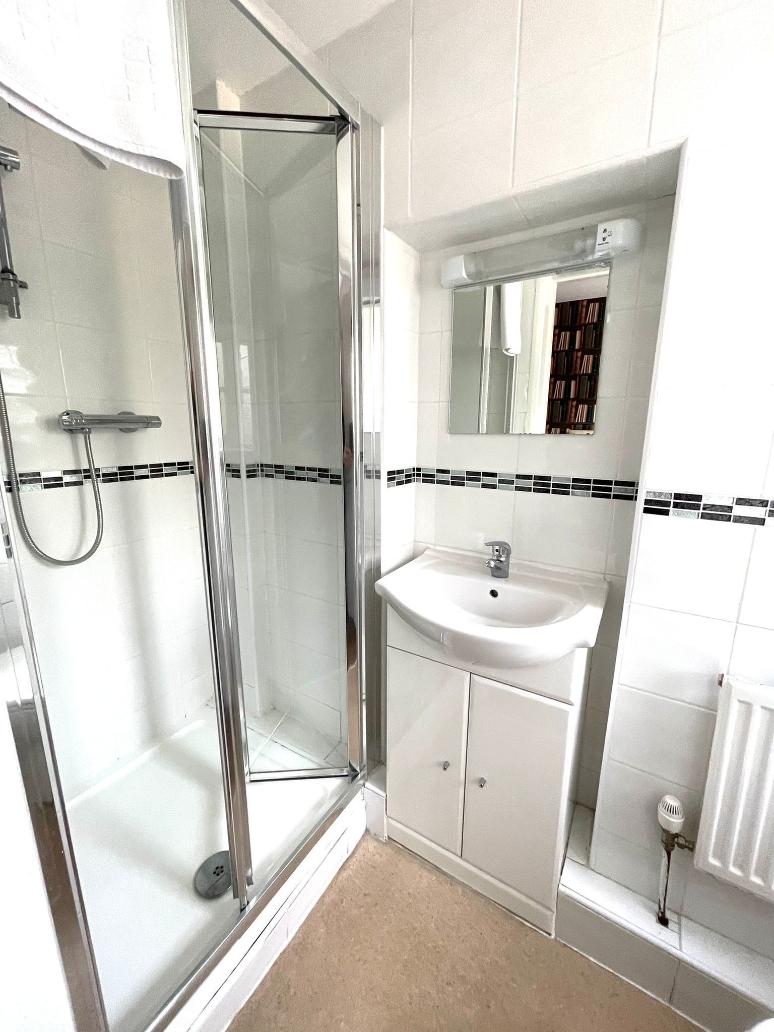 A modern bathroom with a glass shower enclosure, a white sink, and a mirror above it.