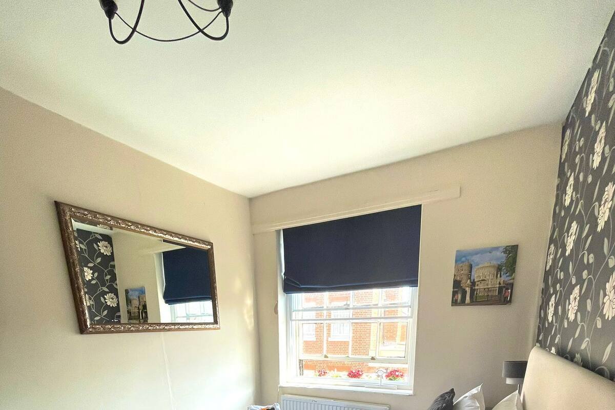 A hotel room with a bed, a dresser, a mirror, a window with a view of buildings, and a radiator.