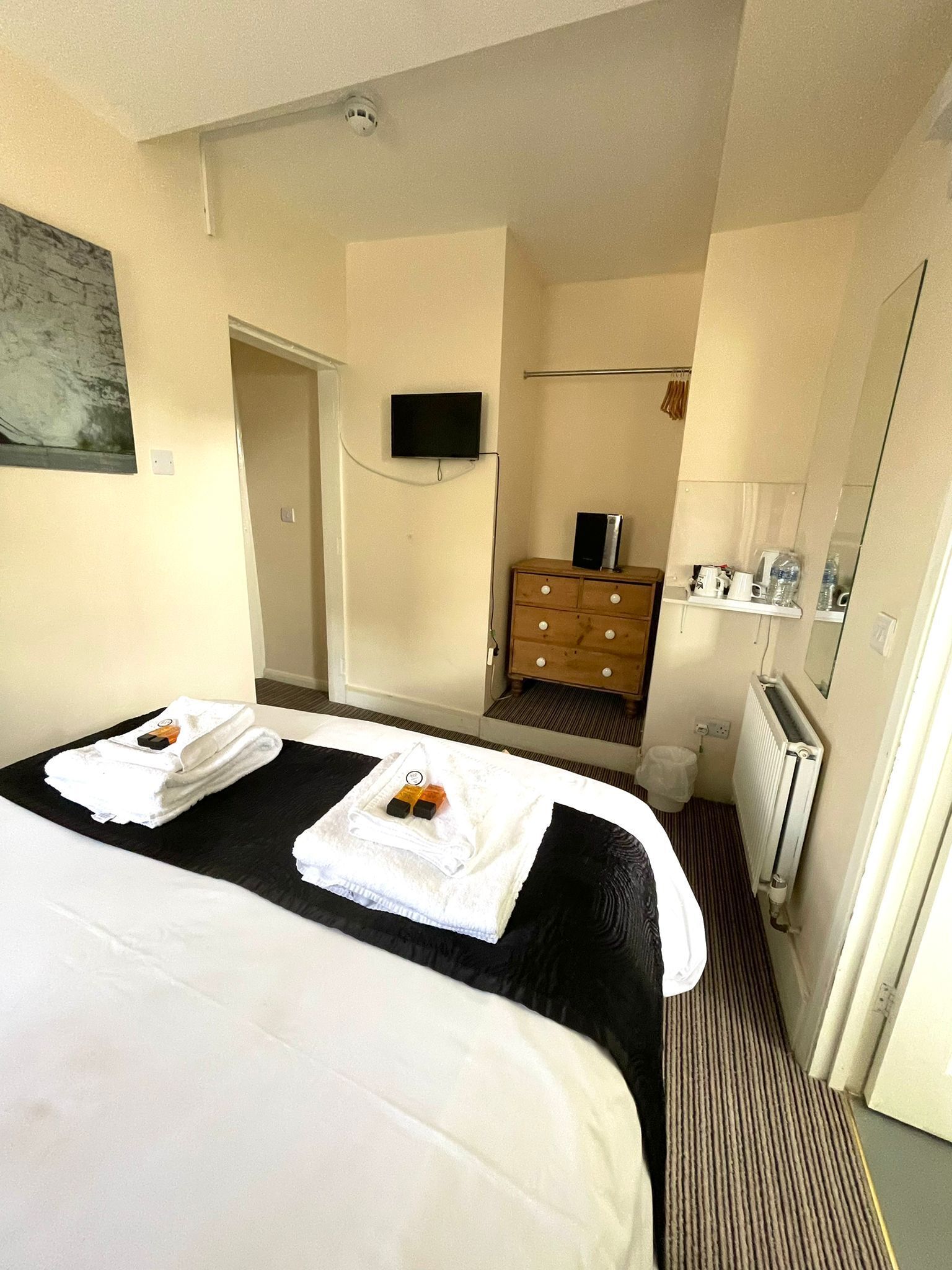 Una habitación de hotel con una cama, un tocador, un televisor y un espejo.