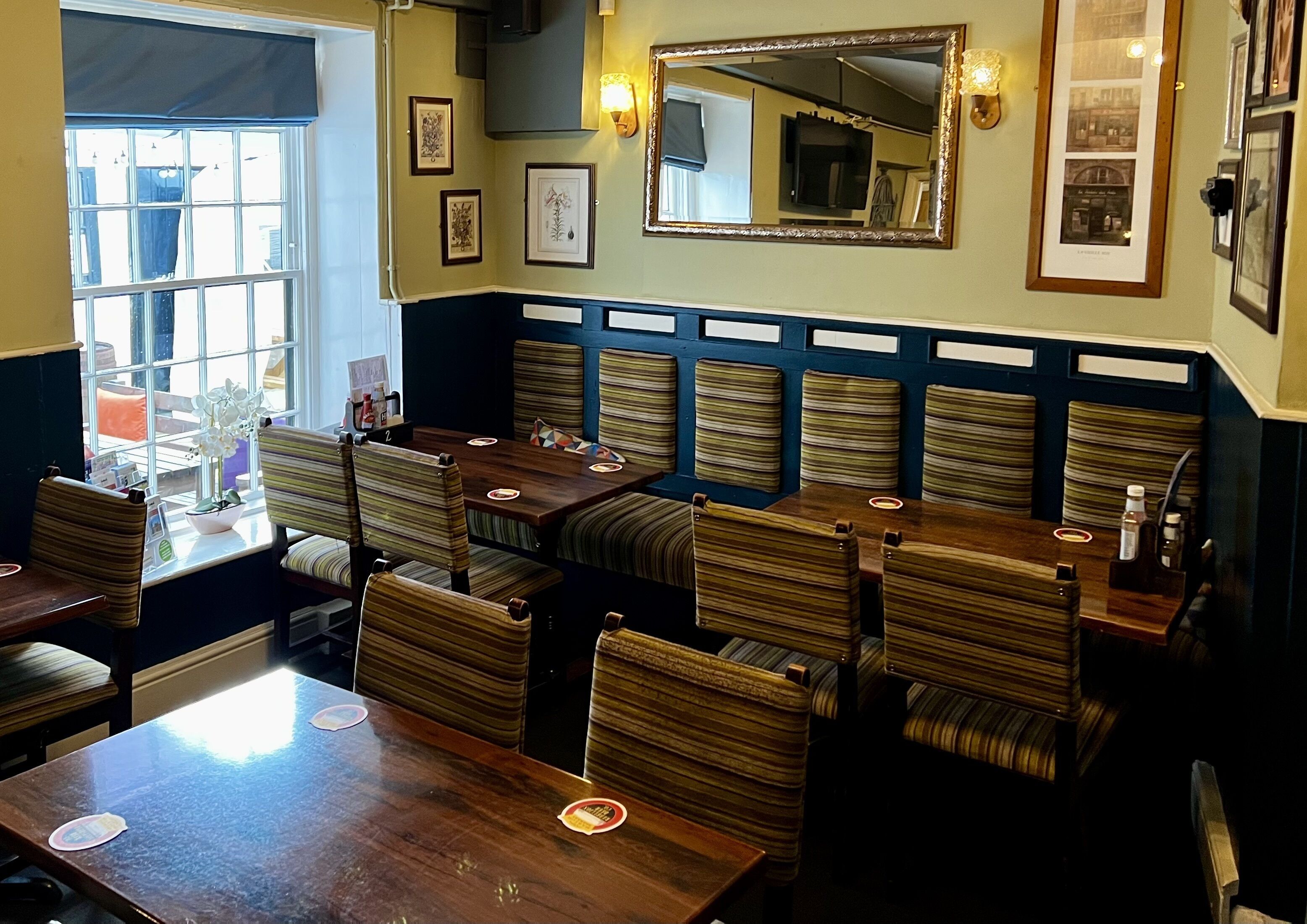 Un restaurant avec des banquettes à carreaux, une table en bois et des tableaux encadrés accrochés aux murs.