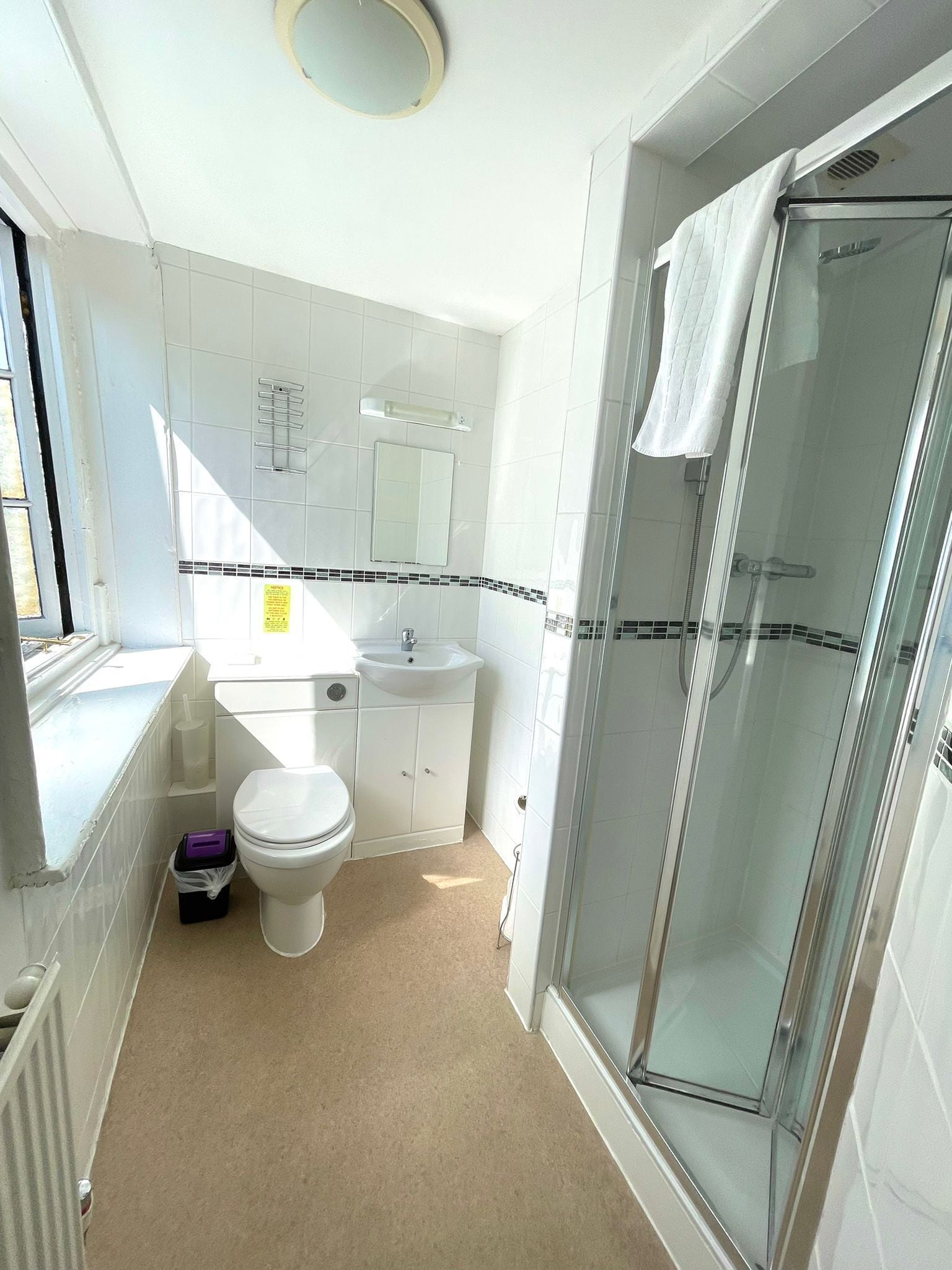 A bathroom with a toilet, sink, and glass shower enclosure.