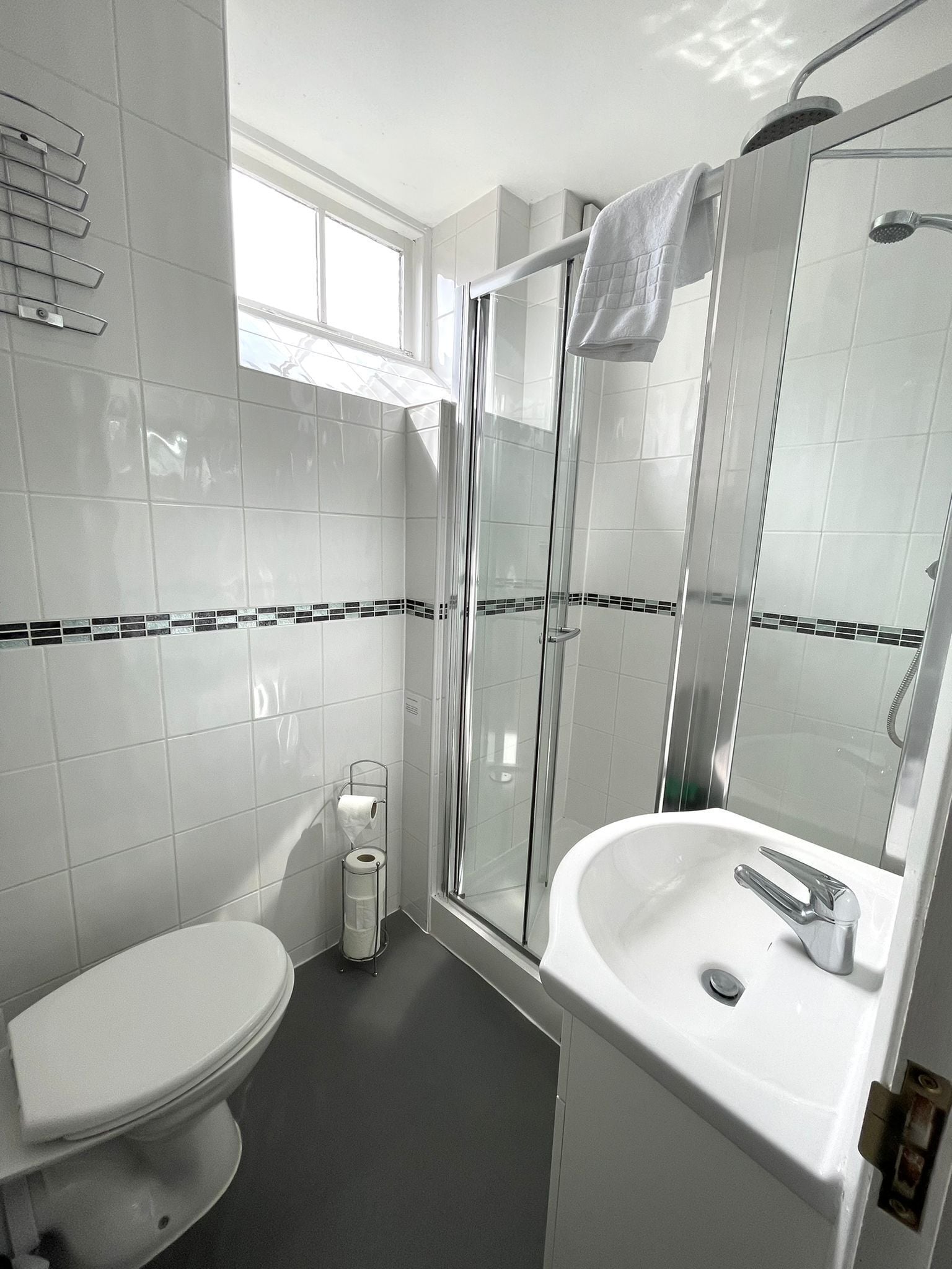 A modern bathroom with a toilet, a glass-enclosed shower, and a sink.
