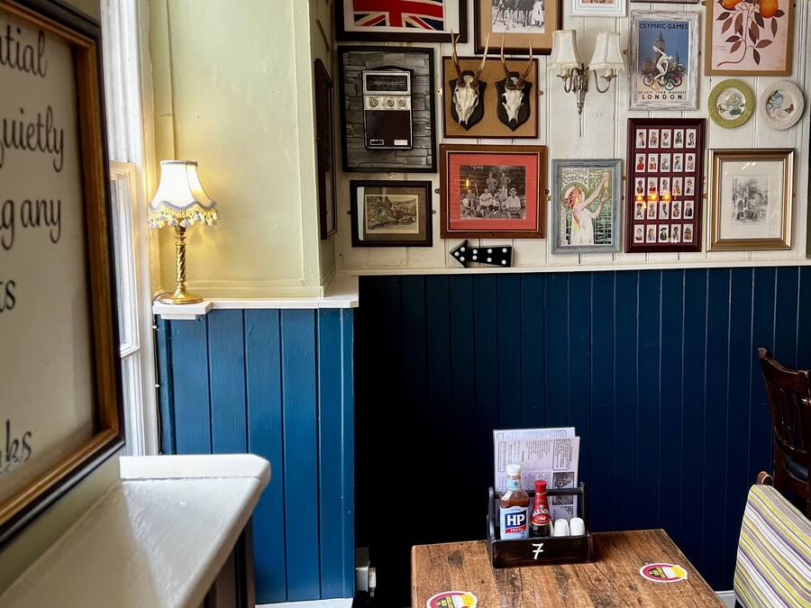 Una habitación con una decoración azul y blanca, que incluye una mesa de madera con un menú, una lámpara y cuadros en la pared.