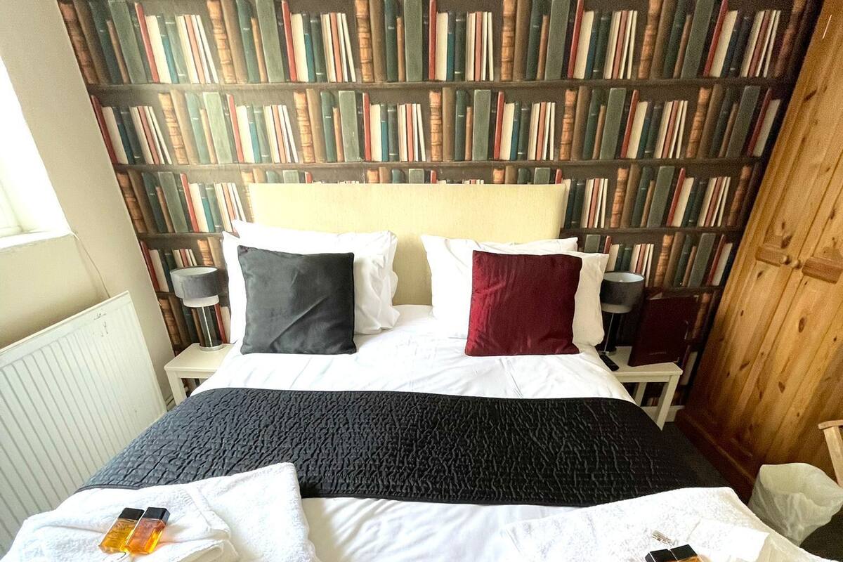 A neatly made bed with white linens and two towels folded at the foot.