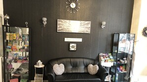 A black leather sofa with heart-shaped pillows, a glass coffee table with a decorative item, and a wall clock. - The Butterfly Hotel - Group Weekends (Blackpool)