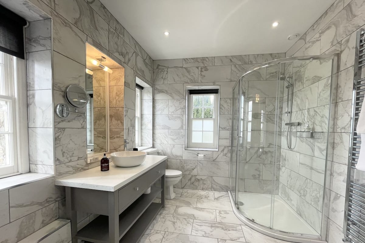 A modern bathroom with a glass-enclosed shower, a vanity with a sink, and a toilet.