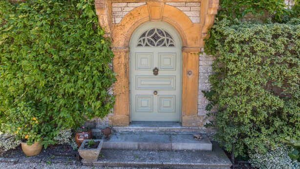A stone entrance with a green door, surrounded by lush greenery. - The Mount Somerton (Somerton)