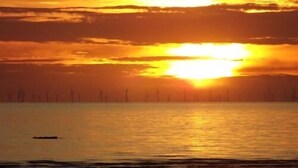 A sunset over a calm sea with wind turbines in the distance. - The New Brooklyn (Blackpool)