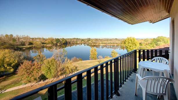 A balcony with a view of a lake, surrounded by trees and a clear sky. - L'Espace Thermal (Dax)