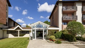 A building with a restaurant entrance, a clear sky, and a well-maintained lawn. - L'Espace Thermal (Dax)