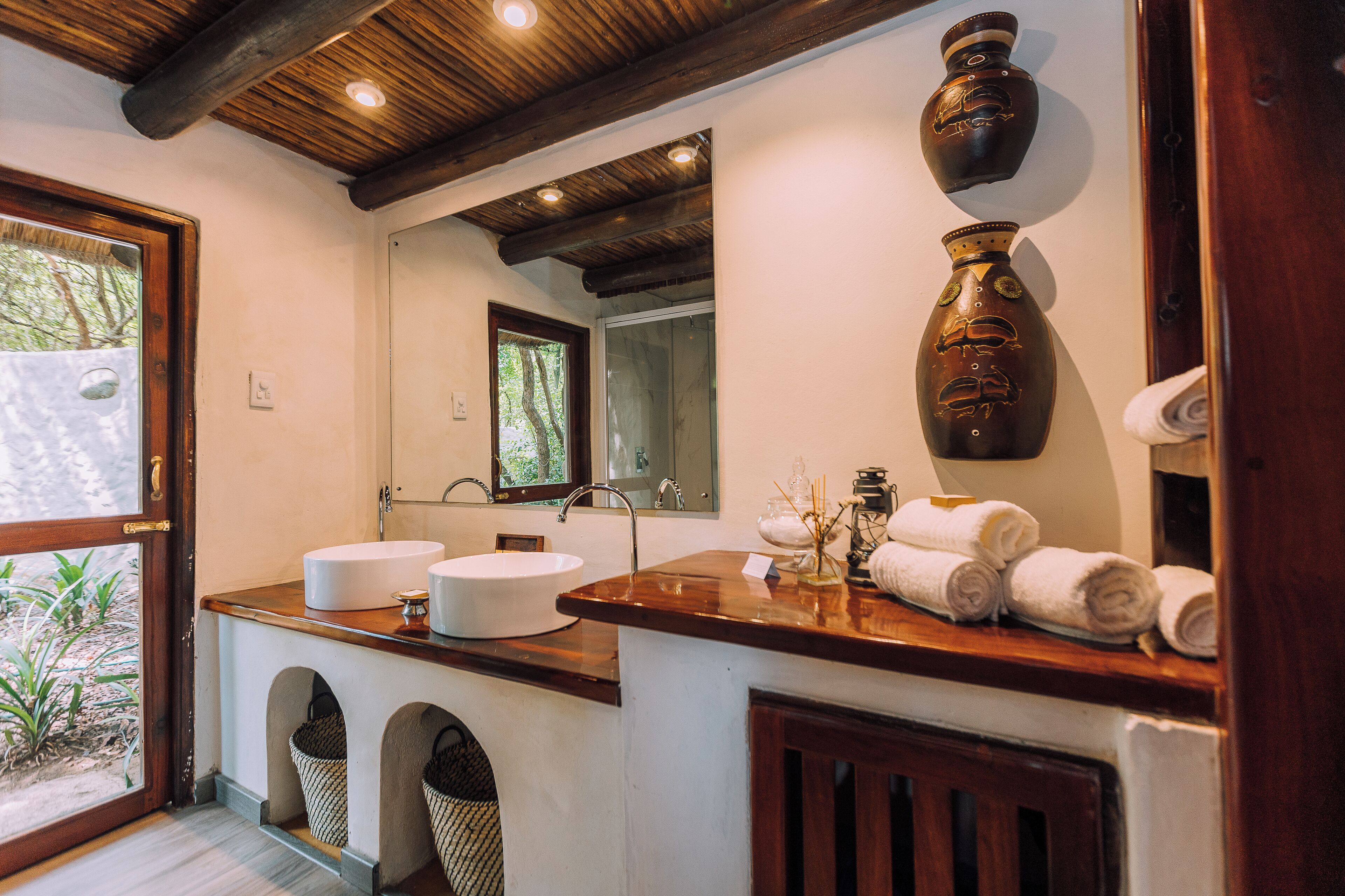 A bathroom with two sinks, a mirror, and a wooden ceiling.