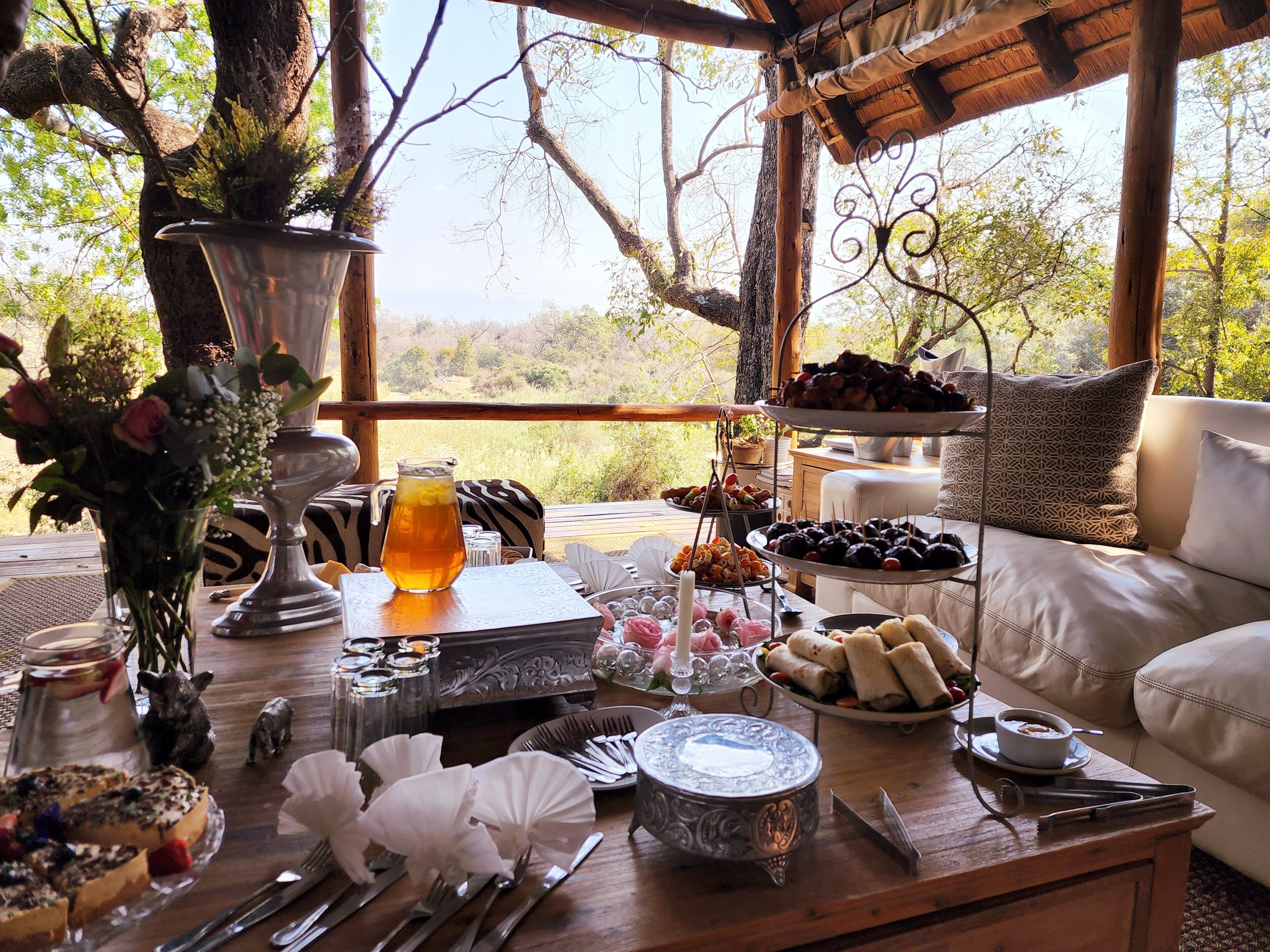 A dining table set with various dishes, a pitcher of tea, and a vase of flowers.