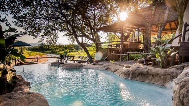 A serene outdoor pool area with natural rock formations, lounge chairs, and a wooden pergola. - Karongwe - Kuname Safari Lodge (Hoedspruit)