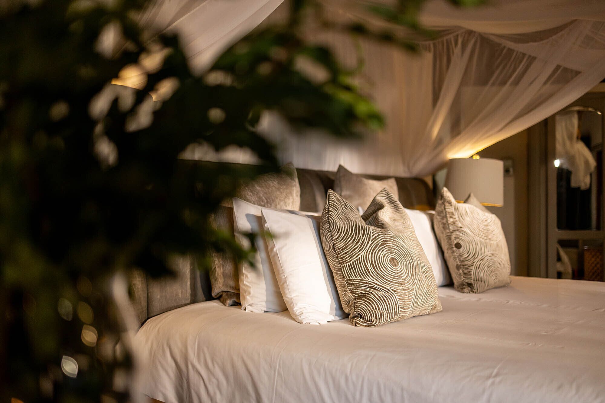Una cama con muchos almohadones y dosel.