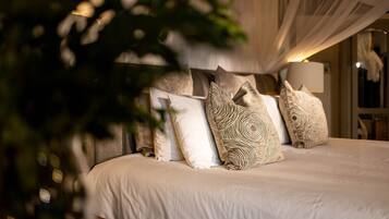 Una cama con muchos almohadones y dosel.