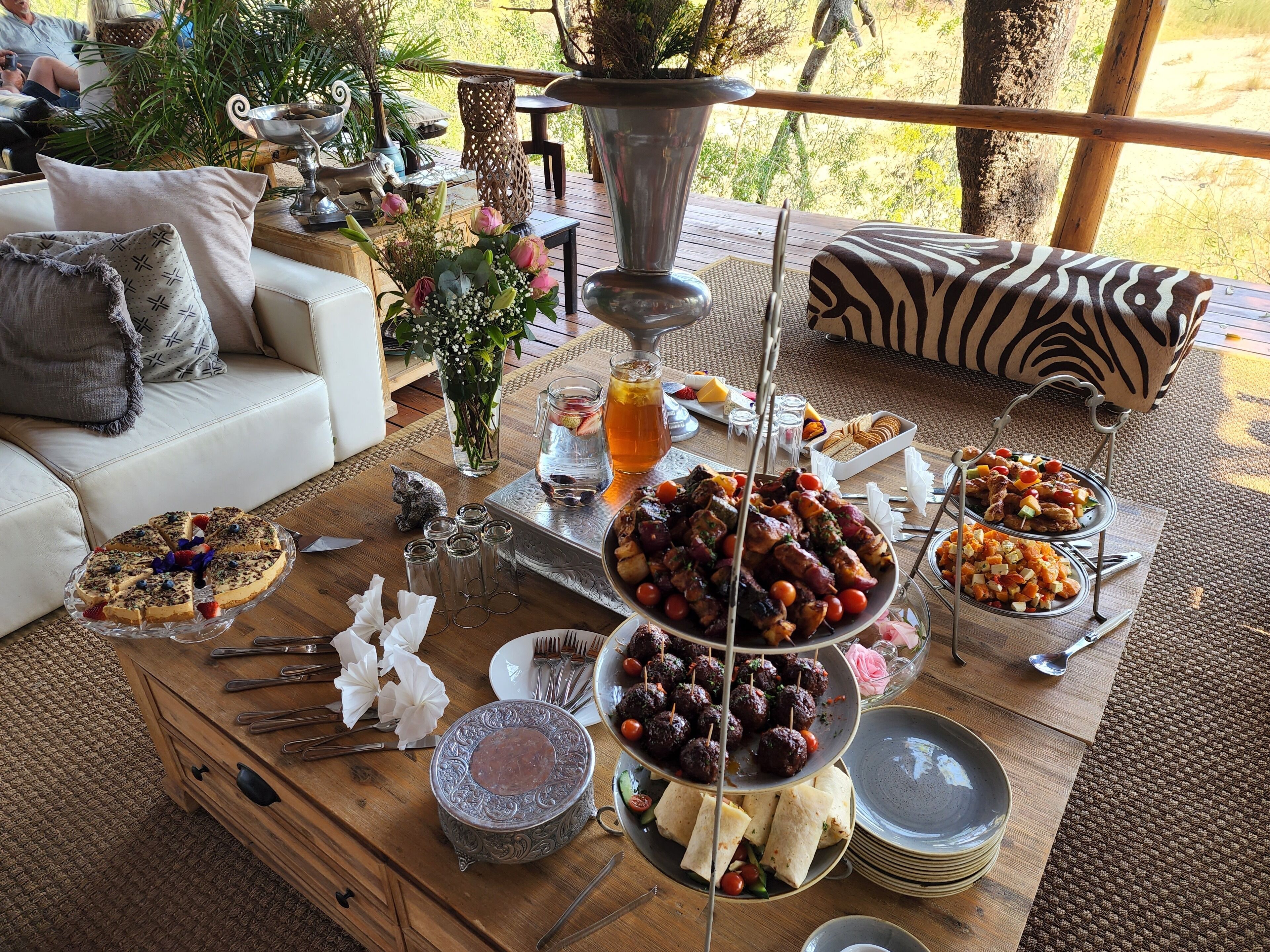 Une table de buffet garnie de différents plats, une chaise à motifs zébrés et un canapé blanc avec des coussins.