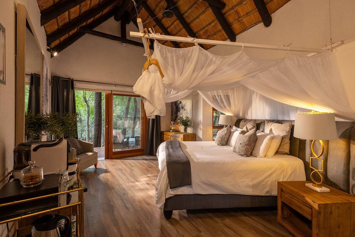 Un dormitorio con cama con dosel, un escritorio de madera con cafetera, y vistas al exterior.