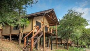 A wooden cabin with a staircase leading to a deck, surrounded by trees. - Karongwe - Chisomo Safari Camp (Tzaneen)