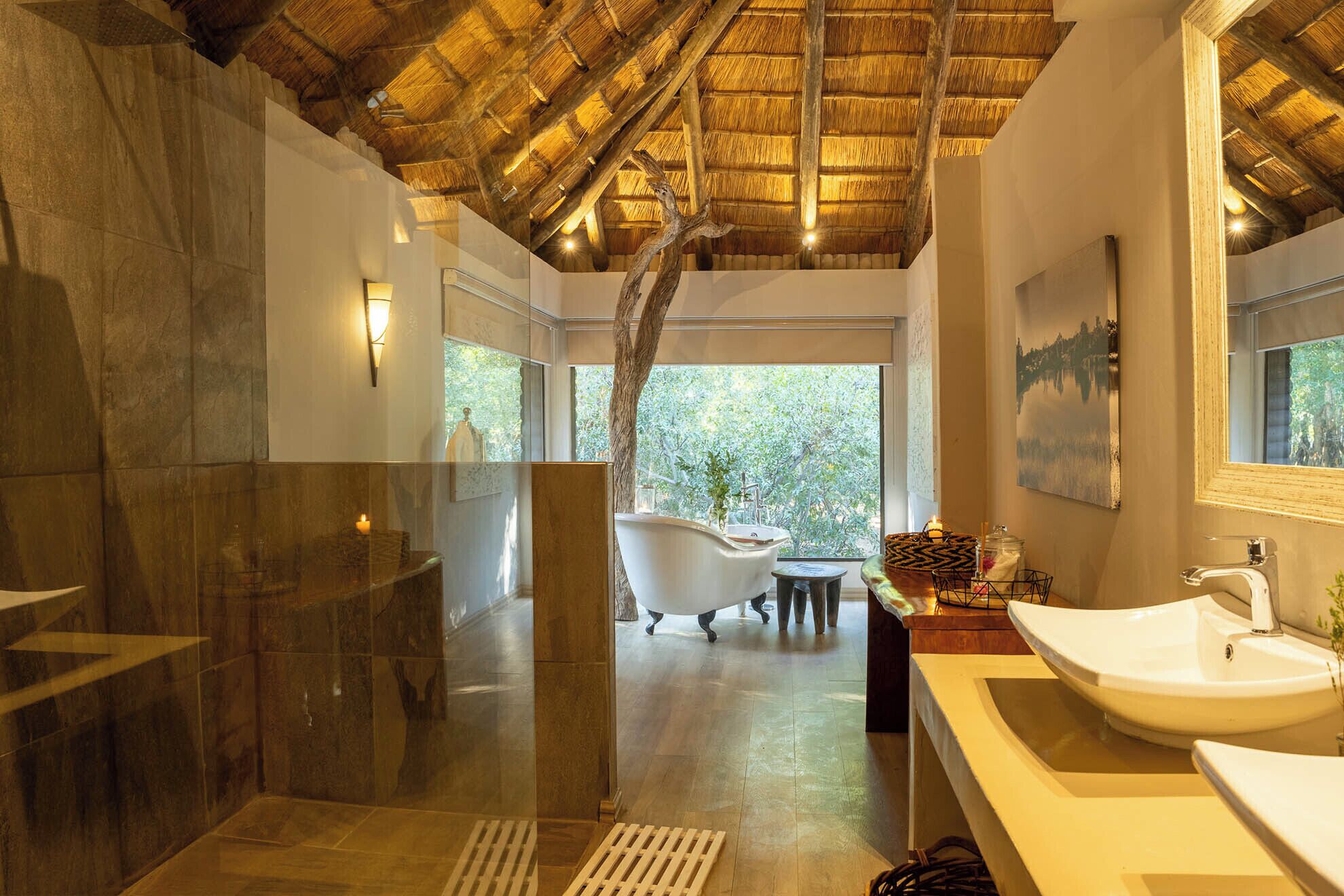 Ein modernes Badezimmer mit einer Badewanne, einem großen Spiegel und Blick ins Grüne.