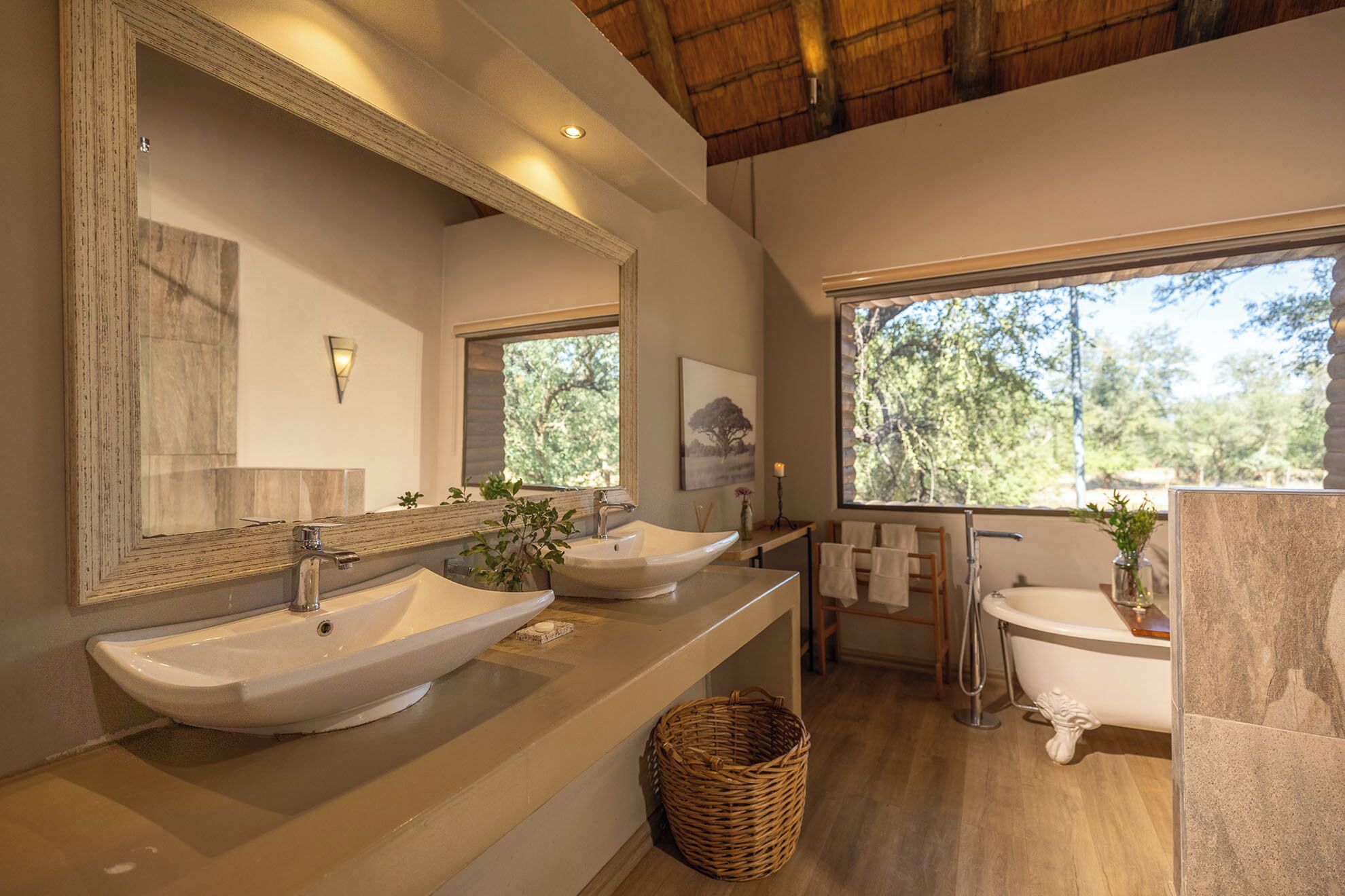 A modern bathroom with two sinks, a large mirror, and a bathtub.