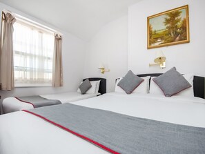 A hotel room with two beds, a painting on the wall, and a window with curtains. - St George Hotel (London)