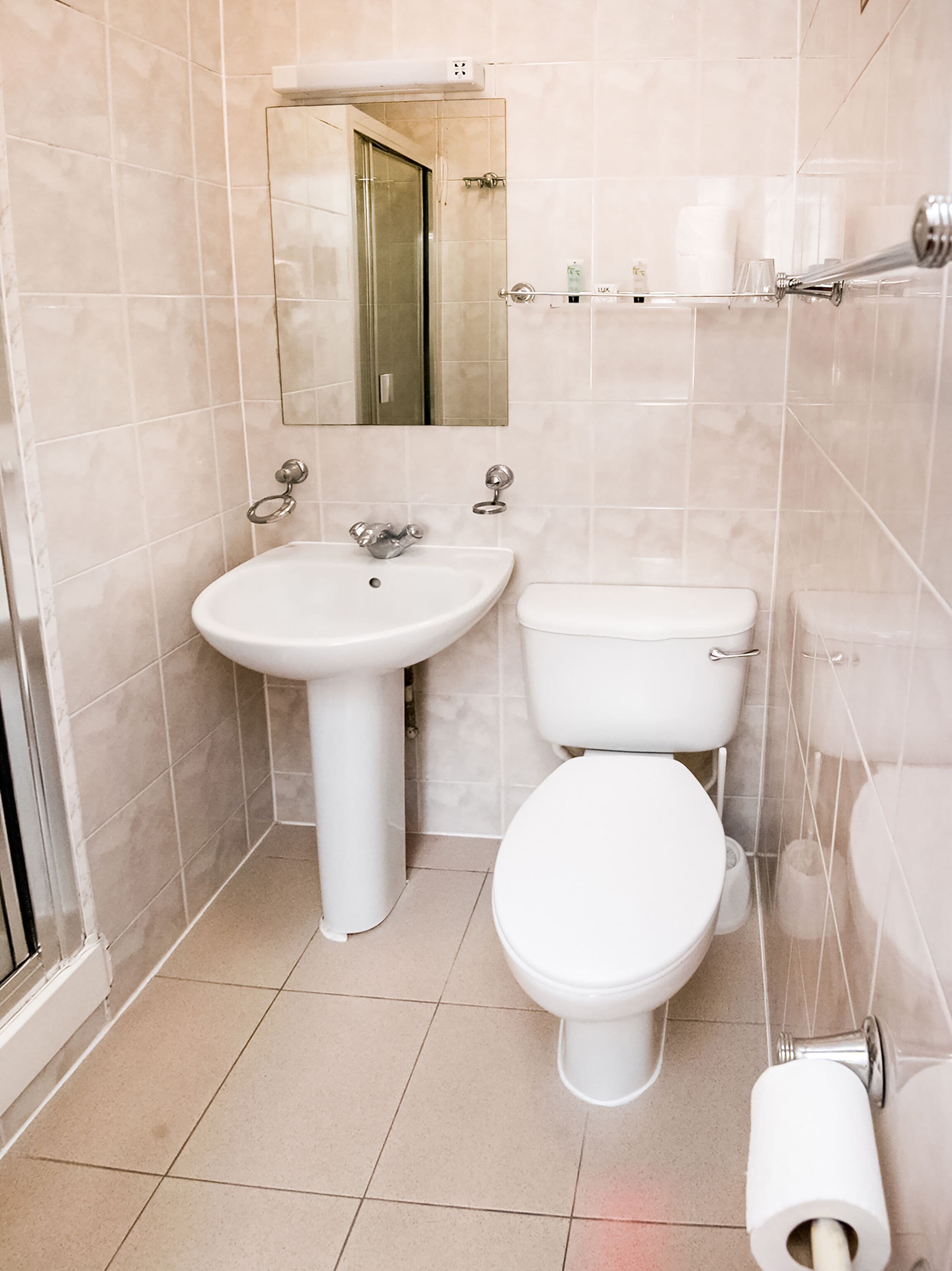 A bathroom with a sink, toilet, and a mirror above the sink.