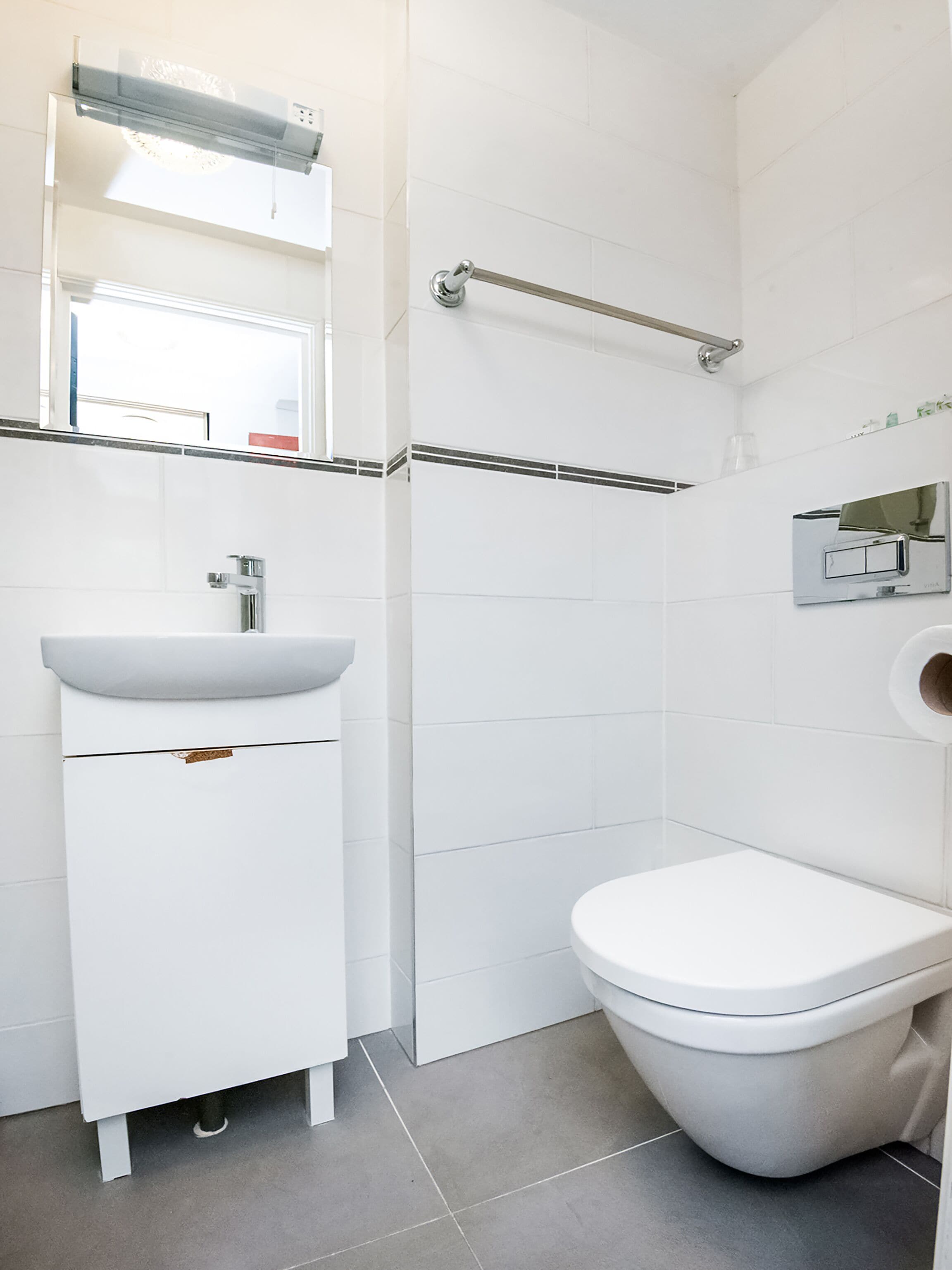 A modern bathroom with a white sink, a toilet, and a shower area.